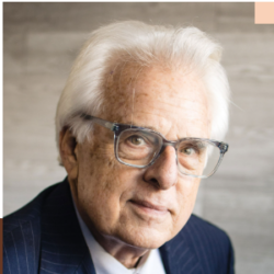 Older man with white hair and glasses, wearing a dark suit. Older man with white hair and glasses, wearing a dark suit.